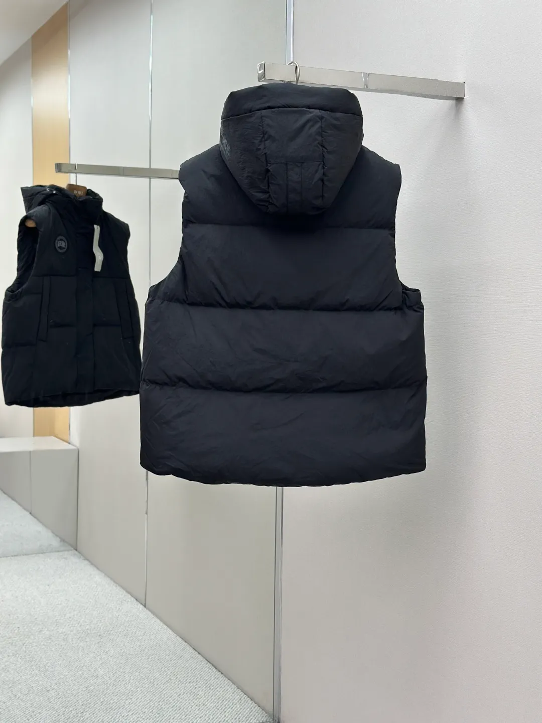 P760 Canada Goose logo hooded down vest Fabric selection: The use of high-quality protective nylon fabric not only enhances the wear resistance of the surface, but also takes into account wind resistance, ensuring excellent performance in various harsh weather conditions.  90 national standard high-quality white duck down: selected high-loft down, weighing 170g, light and warm, with excellent temperature locking performance and good resilience.  Three-dimensional quilting process: Precision thread reinforcement to prevent velvet drilling and ensure that the fluffy and resilient elasticity lasts as new.  Details: Use polyester as the base for woven webbing, and use high-precision computer embroidery to decorate the brand letters on the webbing. The edges of the pattern are clear, the stitches are fine and even, and multiple layers of embroidery threads are stacked to enhance the three-dimensional effect. Accessories: Customized logo Customized zipper pendant Customized hem elastic buckle Customized snap button SIZE: S M L XL